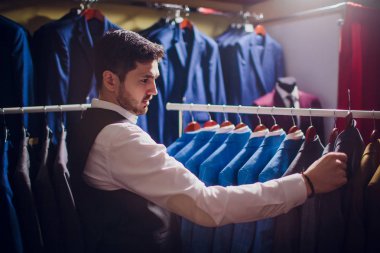 Terzi, terzilik. Erkek takım elbise, terzi atölyesinde. Elegant satırda asılı takım elbise mans. Lüks erkek klasik zarif mens butik rafa uygun.