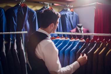 Terzi, terzilik. Erkek takım elbise, terzi atölyesinde. Elegant satırda asılı takım elbise mans. Lüks erkek klasik zarif mens butik rafa uygun.