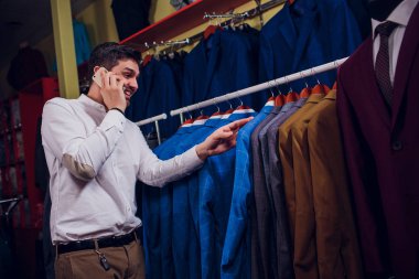 Satış, alışveriş, moda, iletişim ve kavram insanlar - mutlu genç adam veya Smartphone'da arama ve seçme işadamı Giyim Mağazası giyim