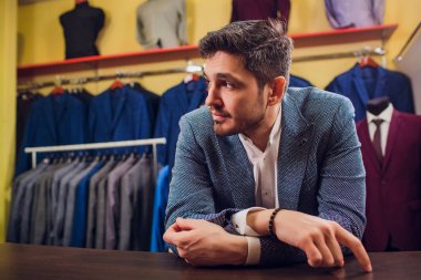 Terzi, terzilik. Erkek takım elbise, terzi atölyesinde. Elegant satırda asılı takım elbise mans. Lüks erkek klasik zarif mens butik rafa uygun. yawns yorgun seçme
