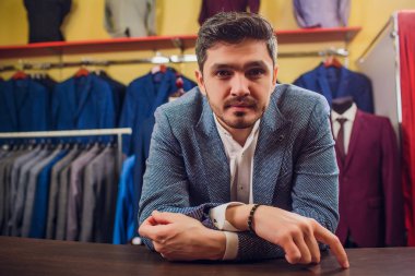 Terzi, terzilik. Erkek takım elbise, terzi atölyesinde. Elegant satırda asılı takım elbise mans. Lüks erkek klasik zarif mens butik rafa uygun. yawns yorgun seçme