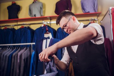 Terzi, terzilik. Erkek takım elbise, terzi atölyesinde. Elegant satırda asılı takım elbise mans. Lüks erkek klasik zarif mens butik rafa uygun. yawns yorgun seçme