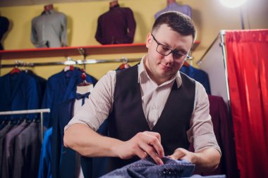 Terzi, terzilik. Erkek takım elbise, terzi atölyesinde. Elegant satırda asılı takım elbise mans. Lüks erkek klasik zarif mens butik rafa uygun. yawns yorgun seçme
