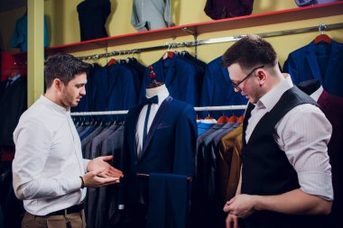 Bir adam mağazadan takım elbise alıyor.