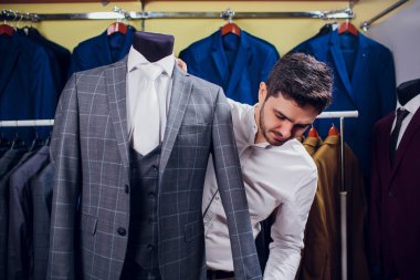 Terzi, terzilik. Erkek takım elbise, terzi atölyesinde. Elegant satırda asılı takım elbise mans. Lüks erkek klasik zarif mens butik rafa uygun.
