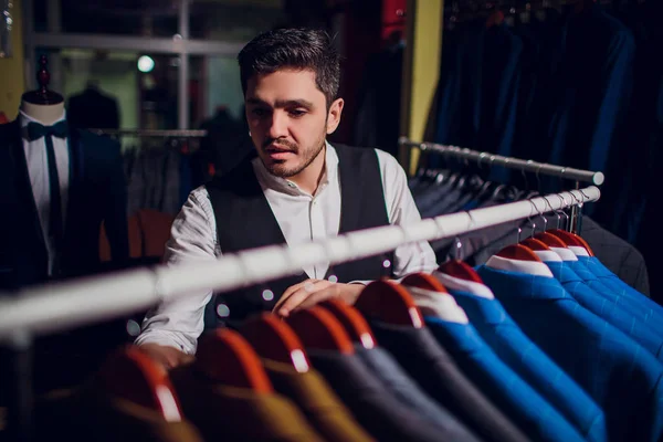 Tailor, tailoring. Mens suit, tailor in his workshop. Elegant mans suits hanging in row. Luxury mens classic suits on rack in elegant mens boutique.