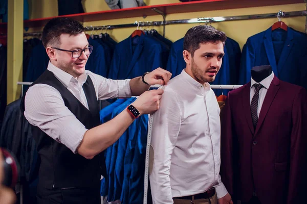 行に対して古典的なベストのビジネスマンは、ショップでスーツします。人により衣料品店でスーツをもう一度やってみる — ストック写真