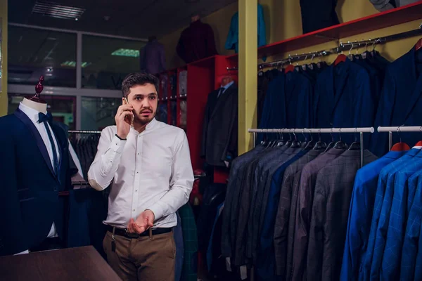 Satış, alışveriş, moda, iletişim ve kavram insanlar - mutlu genç adam veya Smartphone'da arama ve seçme işadamı Giyim Mağazası giyim