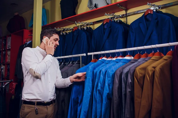 Satış, alışveriş, moda, iletişim ve kavram insanlar - mutlu genç adam veya Smartphone'da arama ve seçme işadamı Giyim Mağazası giyim