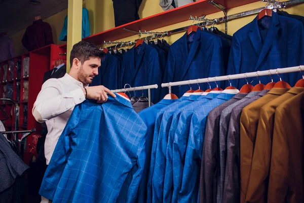 Tailor, tailoring. Mens suit, tailor in his workshop. Elegant mans suits hanging in row. Luxury mens classic suits on rack in elegant mens boutique.