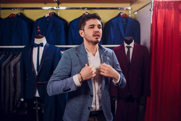 Alfaiate, alfaiataria. Mens terno, alfaiate em sua oficina. Fatos de homem elegantes pendurados na fila. Luxo mens ternos clássicos na cremalheira em elegante mens boutique . — Fotografia de Stock