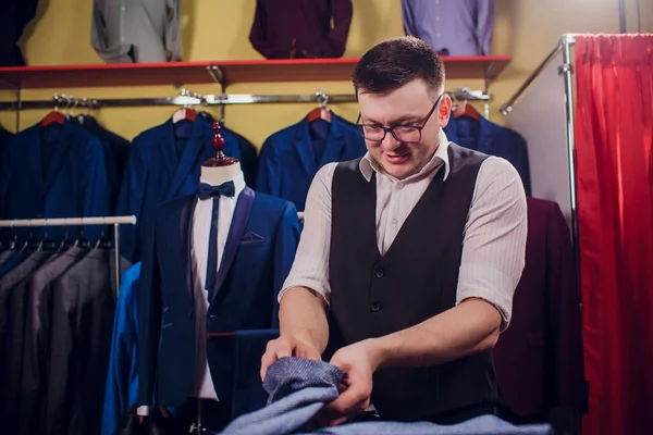 Tailor, tailoring. Mens suit, tailor in his workshop. Elegant mans suits hanging in row. Luxury mens classic suits on rack in elegant mens boutique. yawns tired choosing