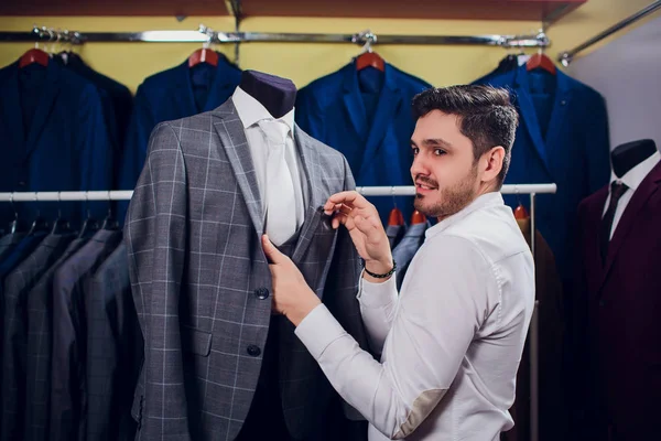 Sartoria, sartoria. Vestito da uomo, sarto nel suo laboratorio. Eleganti abiti da uomo appesi in fila. Vestiti classici da uomo di lusso su rack in elegante boutique da uomo . — Foto Stock