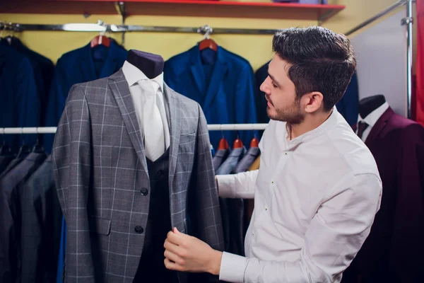 Tailor, tailoring. Mens suit, tailor in his workshop. Elegant mans suits hanging in row. Luxury mens classic suits on rack in elegant mens boutique.