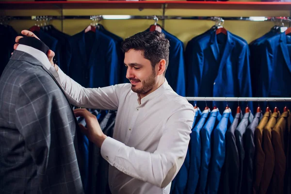 Tailor, tailoring. Mens suit, tailor in his workshop. Elegant mans suits hanging in row. Luxury mens classic suits on rack in elegant mens boutique.