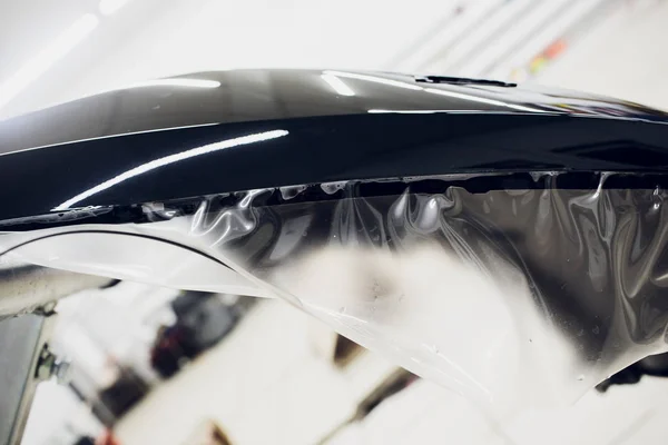Manos de trabajador instala protección de pintura del coche película envoltura parachoques — Foto de Stock