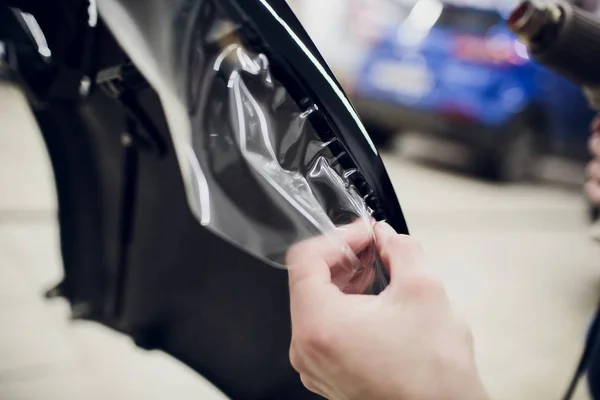 Manos de trabajador instala protección de pintura del coche película envoltura parachoques — Foto de Stock