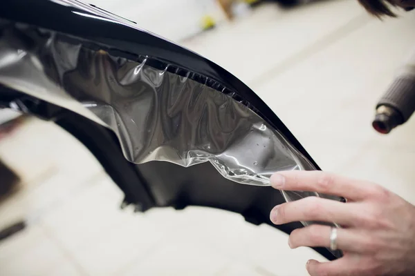 Werknemer handen installeert auto verf bescherming film wrap bumper — Stockfoto