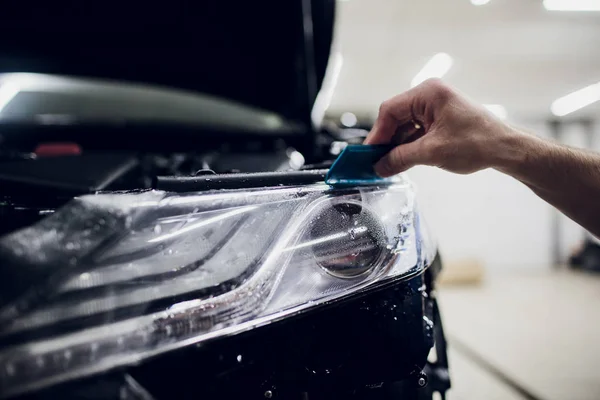 Manos de trabajador instala protección de pintura del coche película envoltura auto faro — Foto de Stock
