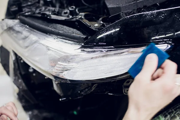 Рука працівника встановлює автомобільний захист фарби плівки обгортки авто фари — стокове фото