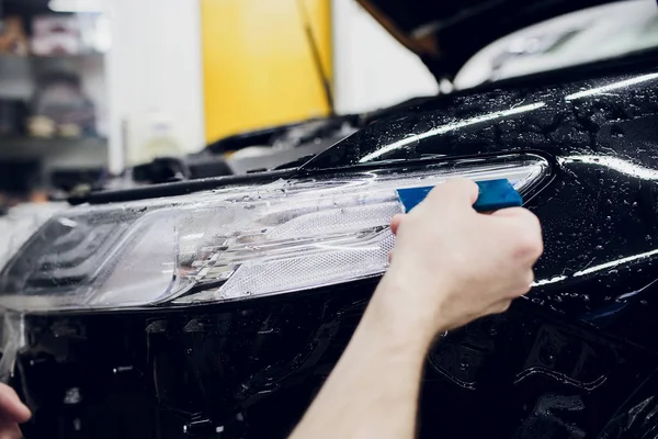 Εργαζόμενος χέρια εγκαθιστά προβολέας auto wrap ταινία προστασίας βαφής αυτοκινήτου — Φωτογραφία Αρχείου