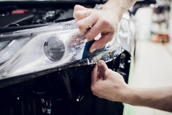 Le mani del lavoratore installa auto pellicola di protezione della vernice avvolgere faro automatico — Foto Stock
