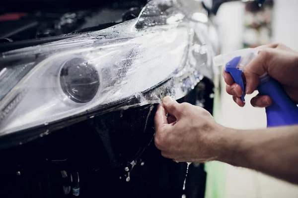 Werknemer handen installeert auto verf bescherming film wrap Automatische koplamp — Stockfoto