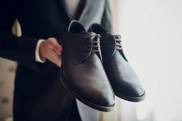 Grooms morning. Wedding accessories. Shoes. The groom ties hoelaces on his shoes