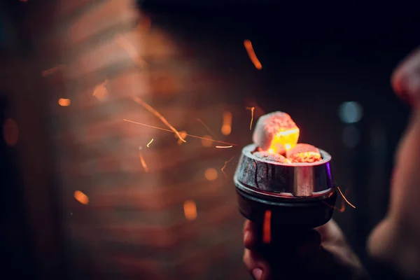 Bowl of the hookah with red hot coals in the hands of a hookah on a dark background Smoking — Stock Photo, Image