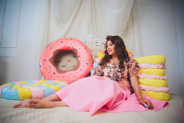 Bonito menina posando com rosa donuts, brincando, sobremesa, comida ruim, olha para o buraco no donut, mantém donuts pelos olhos — Fotografia de Stock