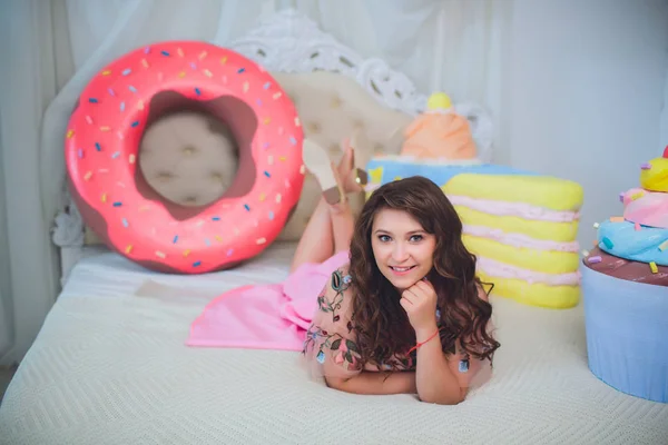 Bonito menina posando com rosa donuts, brincando, sobremesa, comida ruim, olha para o buraco no donut, mantém donuts pelos olhos — Fotografia de Stock