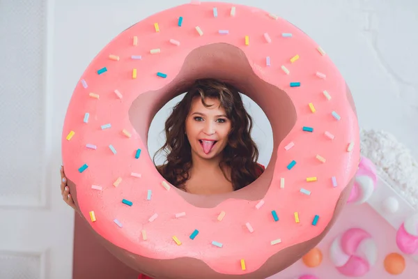 Jolie fille posant avec des beignets roses, s'amuser autour, dessert, mauvaise nourriture, regarde dans le trou dans le beignet, garde les beignets par les yeux — Photo