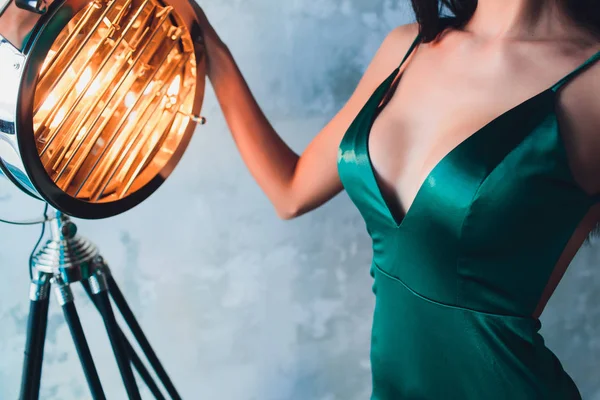 Décolleté, belle grande poitrine féminine, robe verte, gros plan. projecteurs de cinéma en aluminium — Photo