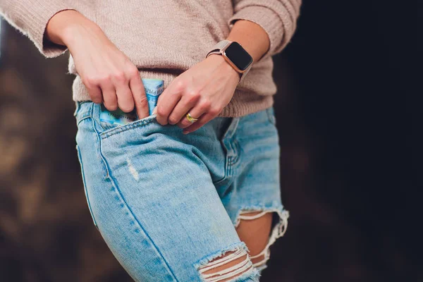 Flicka sätter pengar i en ficka jeans tillbaka papper räkningar 200 och 2000 rubel. — Stockfoto