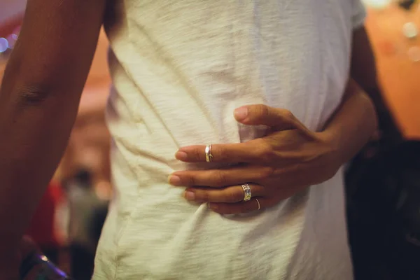 Cerca de las manos de la atractiva pareja joven. Hombre con camisa vaquera y jeans. Mujeres manos abrazando hombre . — Foto de Stock