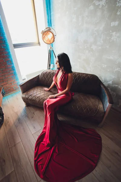 Foto estúdio de moda de mulher linda com cabelo escuro e maquiagem à noite, usa vestido vermelho luxuoso. luzes turquesa neon holofotes filme — Fotografia de Stock