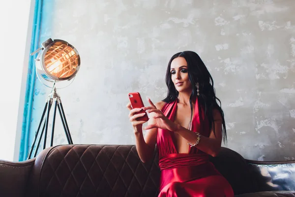 Foto studio di moda di splendida donna con i capelli scuri e trucco serale, indossa lussuoso vestito rosso. luci al neon turchese riflettore del film fa un selfie — Foto Stock