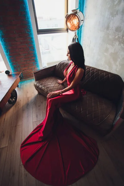 黒い髪と夜メイク、身に着けている豪華な赤いドレスでゴージャスな女性のファッション スタジオ写真。ターコイズ ブルーのネオン ライト映画スポット ライト — ストック写真