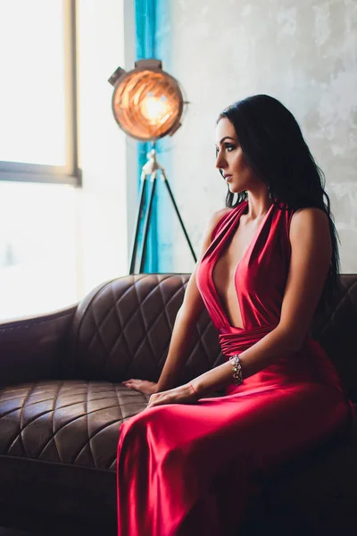 Foto de estudio de moda de mujer hermosa con cabello oscuro y maquillaje de noche, lleva vestido rojo de lujo. luces turquesa neón proyector de película — Foto de Stock