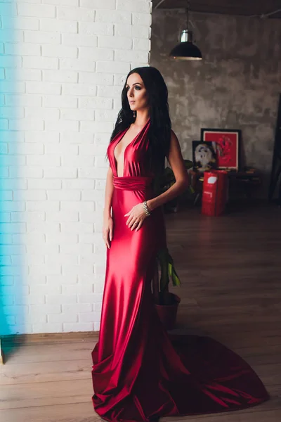 Foto de estudio de moda de mujer hermosa con cabello oscuro y maquillaje de noche, lleva vestido rojo de lujo. luces de neón turquesa — Foto de Stock