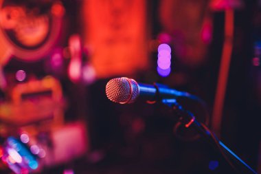 Mikrofon bir stand için hazır canlı müzik performansı veya karaoke gecesi yumuşak bokeh ışıkları ve insan siluetleri ile arka planda. Kavramı için müzik şarkı olay, iyi vakit geçiriyor.