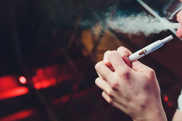 Tecnologia dei prodotti del tabacco non bruciati termicamente IQOS. Uomo che tiene la sigaretta elettronica in mano prima di fumare . — Foto Stock