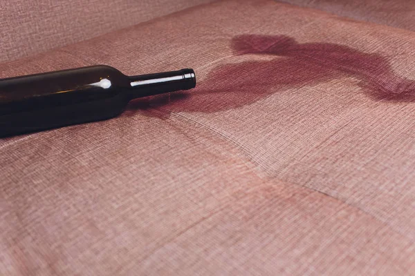 Vino rosso versato su un divano marrone. bottiglia scura di vino rosso caduto — Foto Stock