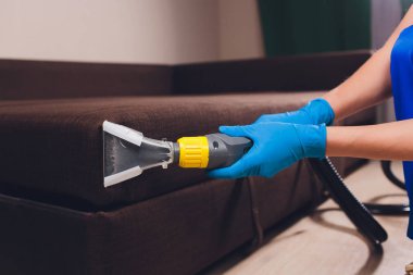 Kanepe kimyasal profesyonel çıkarma yöntemiyle Temizleme. Döşemeli mobilya. Erken bahar temizlik veya normal temizleyin. Kir kaldırmak ışık mavi koruyucu eldiven çalışan Kuru Temizleme