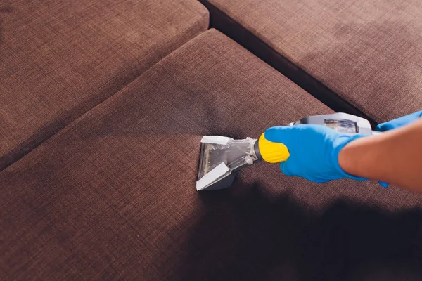 Kanepe kimyasal profesyonel çıkarma yöntemiyle Temizleme. Döşemeli mobilya. Erken bahar temizlik veya normal temizleyin. Kir kaldırmak ışık mavi koruyucu eldiven çalışan Kuru Temizleme