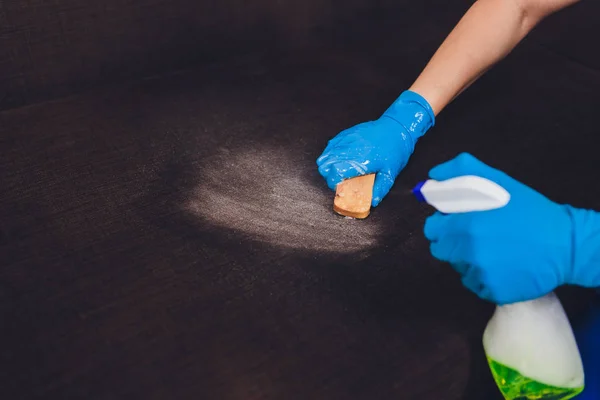 Imagem cortada. Conceito de limpeza. Mão masculina em luvas de proteção limpando sofá sofá na sala . — Fotografia de Stock