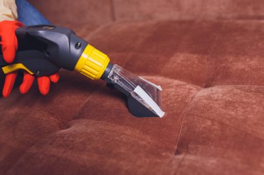 Kanepe kimyasal profesyonel çıkarma yöntemiyle Temizleme. Döşemeli mobilya. Erken bahar temizlik veya normal temizleyin. Kir kaldırmak ışık kırmızı koruyucu eldiven çalışan Kuru Temizleme