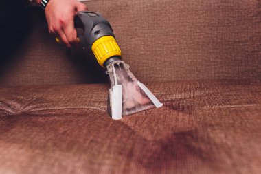 Kanepe kimyasal profesyonel çıkarma yöntemiyle Temizleme. Döşemeli mobilya. Erken bahar temizlik veya normal temizleyin. Kir kaldırmak ışık koruyucu eldiven çalışan Kuru Temizleme