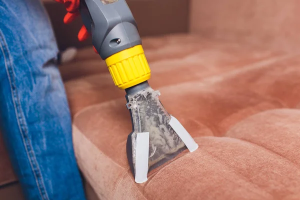 Sofa chemical cleaning with professionally extraction method. Upholstered furniture. Early spring cleaning or regular clean up. Dry cleaners in light red protective glove employee removing dirt from — Stock Photo, Image