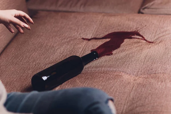Vino rosso versato su un divano marrone. bottiglia scura di vino rosso caduto — Foto Stock